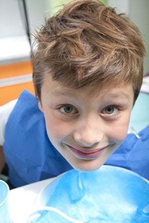 up-close image of a child smiling in a dentist's chair